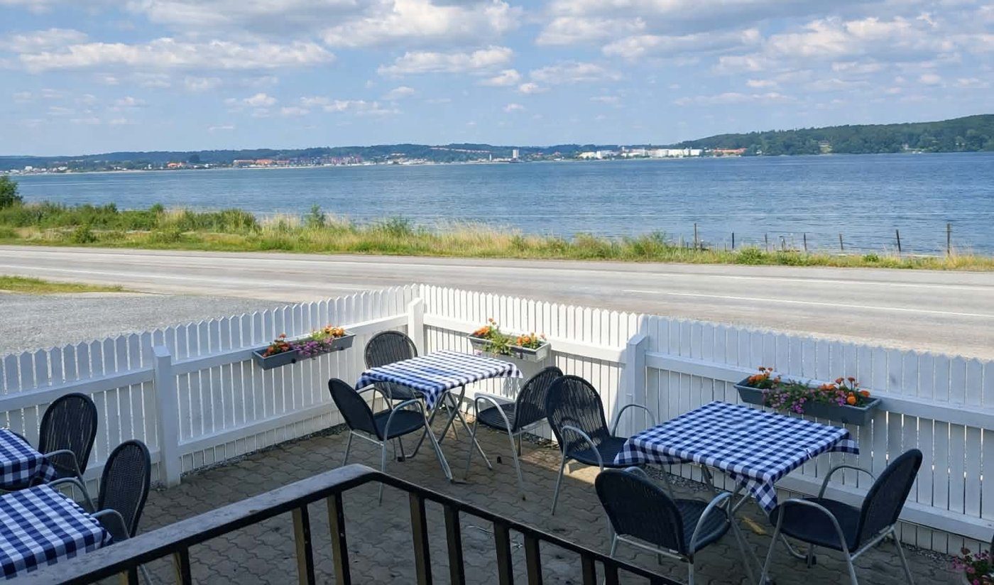 Terrassen med ternede duge og udsigt over vejen og fjorden til Aabenraa